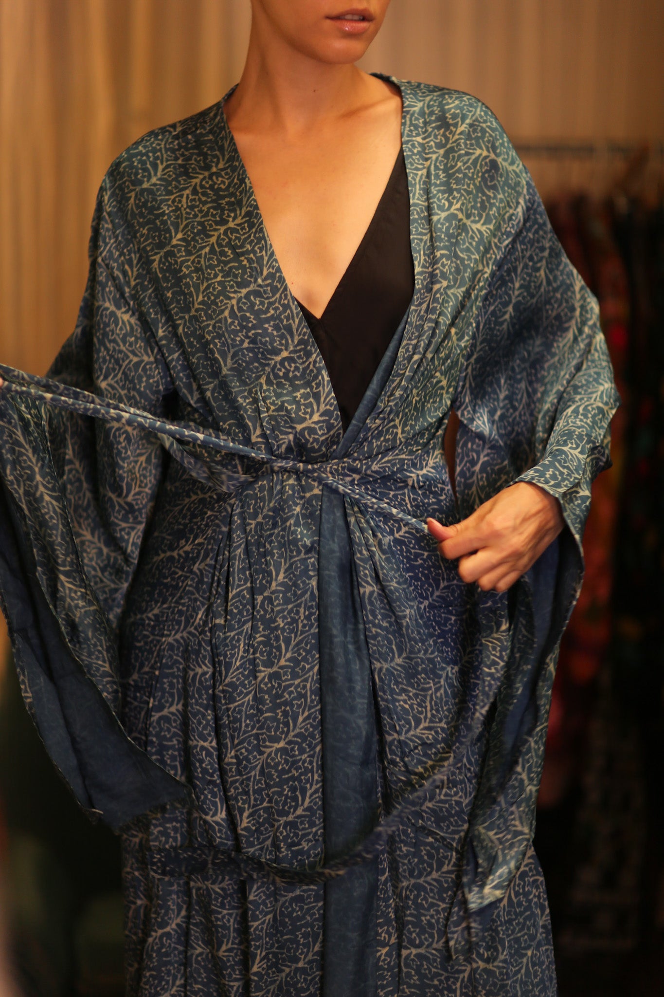 Person wearing a blue patterned robe over a black top against a blurred background